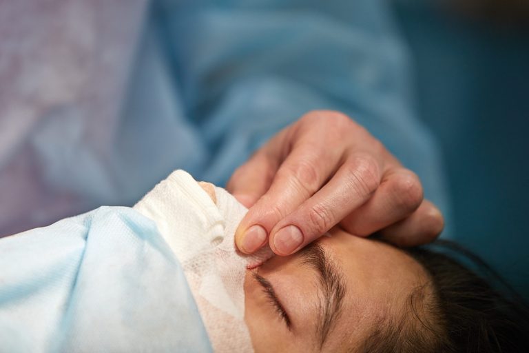Manos de un cirujano explorando el rostro de una paciente